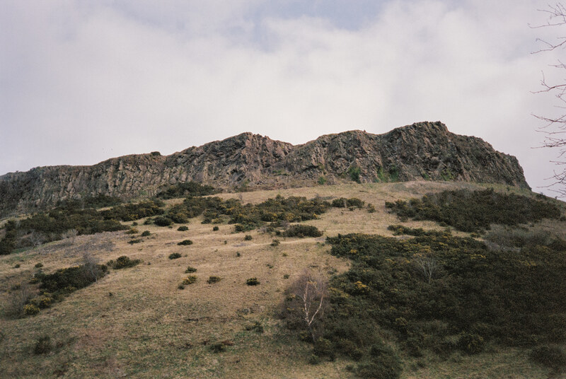 Rocky cliffs above a grassy hillside.